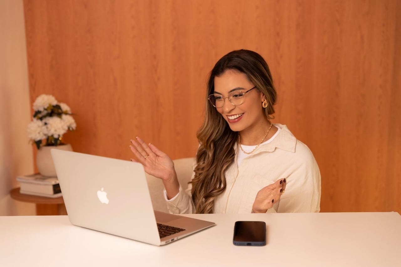 Yasmin Lopes sorrindo durante uma sessão de psicoterapia online, diante do computador