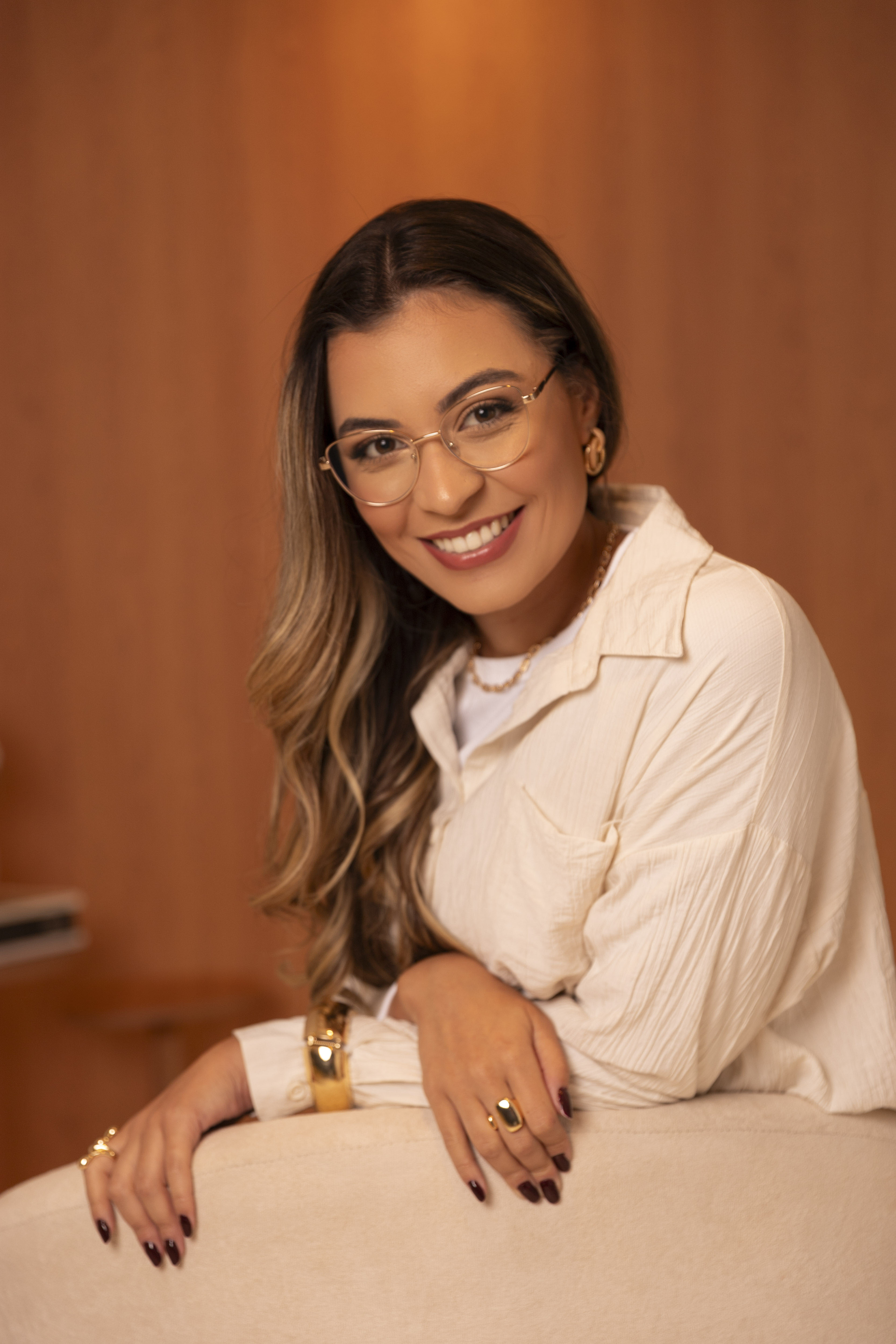 Retrato de Yasmin Lopes sorrindo, apoiada no encosto de uma poltrona no consultório