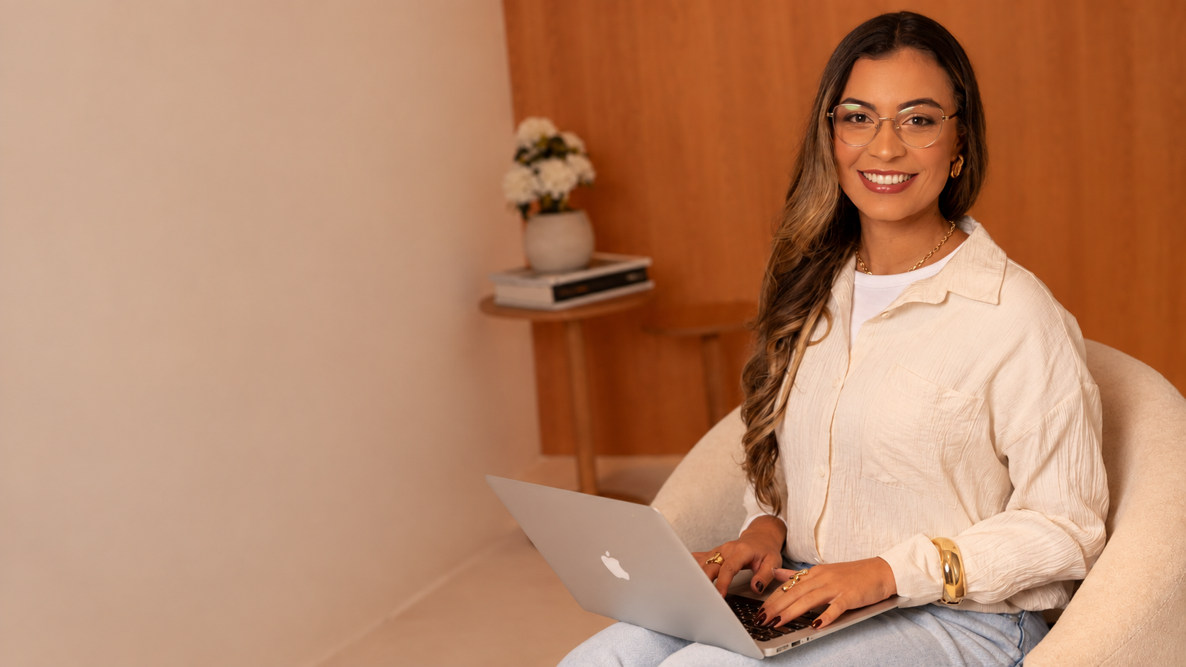 Yasmin Lopes, psicóloga, sentada em uma poltrona com o notebook no colo durante um atendimento online
